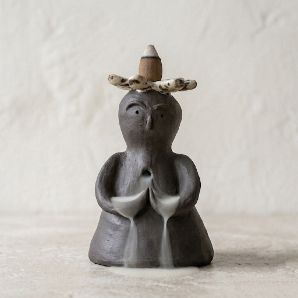 Handmade ceramic backflow incense burner statue with a flower crown and soft smoke waterfall effect.