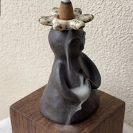 Close up of a handmade ceramic backflow incense burner with speckled flower crown and gentle smoke flow.