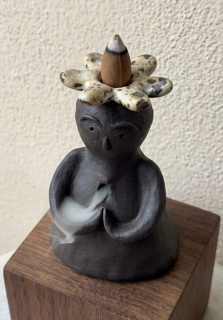 Handmade ceramic incense burner statue with a flower crown and rising backflow smoke for a calm home atmosphere.