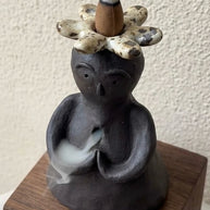 Handmade ceramic incense burner statue with a flower crown and rising backflow smoke for a calm home atmosphere.