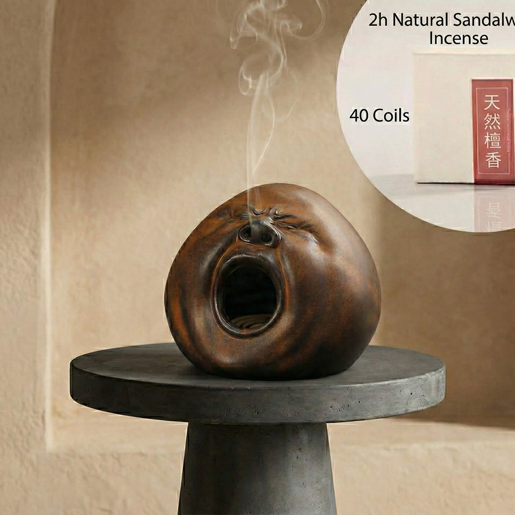 Handmade ceramic yawning face incense burner displayed with sandalwood incense coils packaging and smoke drifting from the face opening