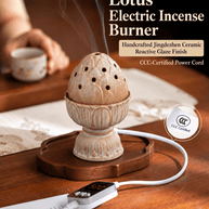 Lotus ceramic electric incense burner releasing wisps of smoke on a wooden tray beside a teacup, with its digital controller.