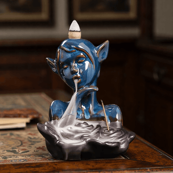 Blue ceramic mischief spirit backflow burner with smoke flowing into basin.