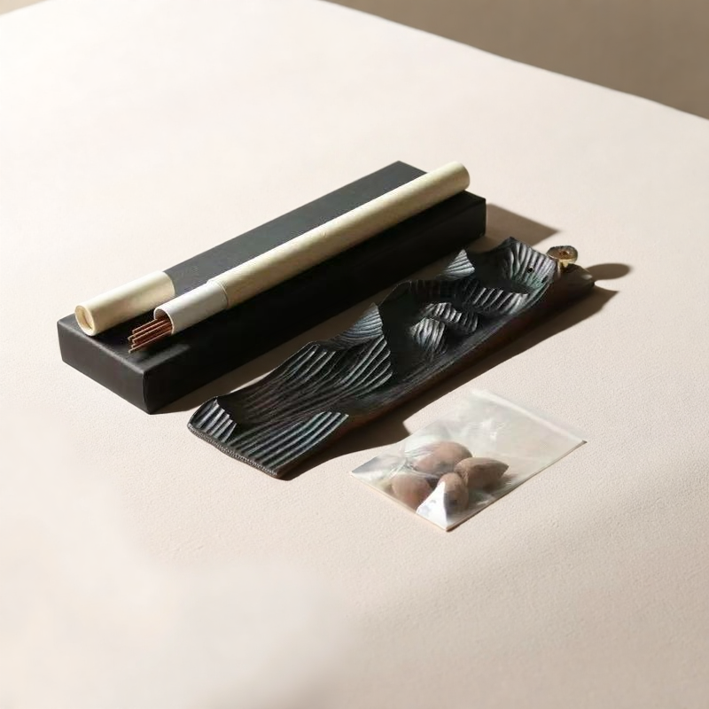 Black wooden Mountain Mist incense burner set laid out on neutral surface with incense sticks, scroll, and cones in a minimalist flatlay arrangement