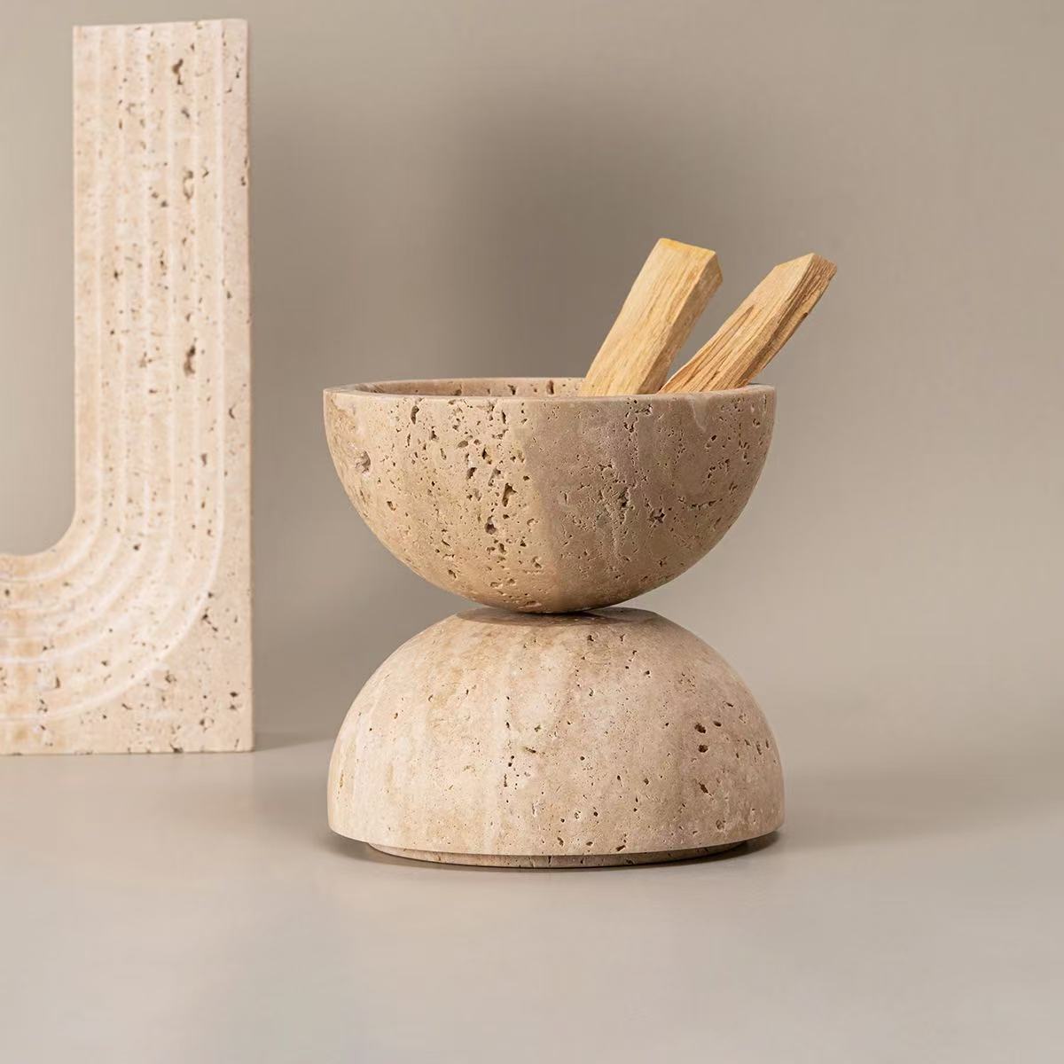 Two halves of a natural travertine incense burner placed open with palo santo sticks inside, showcasing stone texture and storage function