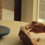 Short video of an artisan sculpting the clay flame incense holder and tray by hand on a workbench.