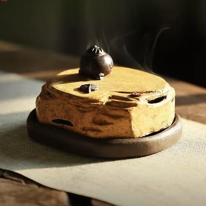 Side view of purple clay incense burner with landscape lid and visible smoke flowing from the top