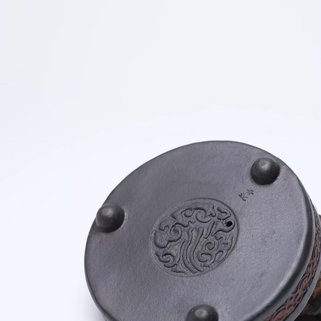 Bottom view of the rock-form purple clay incense burner showing carved seal and three support feet
