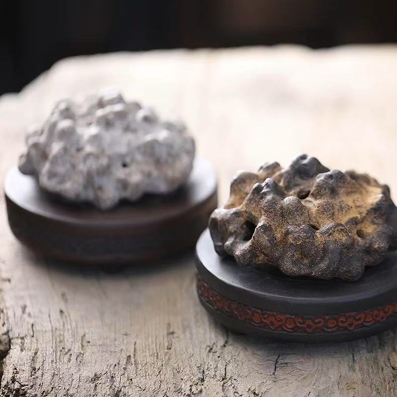Two rock-form purple clay incense burners side by side, showcasing light gray and dark brown variations on a wooden surface
