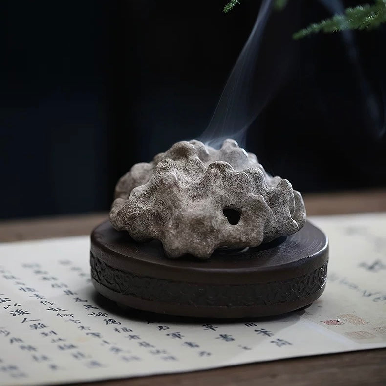 Rock-form handmade purple clay incense burner in Tear White color, emitting smoke on tabletop
