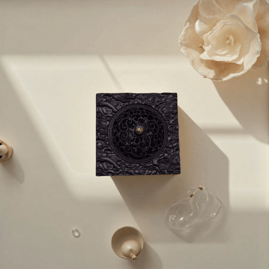 Top view of vintage black ebony incense burner placed in a decorative flat lay scene with dried rose, shadow play, and ceramic accessories