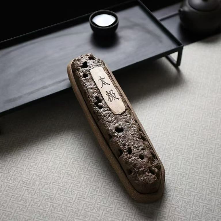 Top-down view of handmade volcanic ceramic incense holder with "太极" label, placed on patterned mat with tea set in background