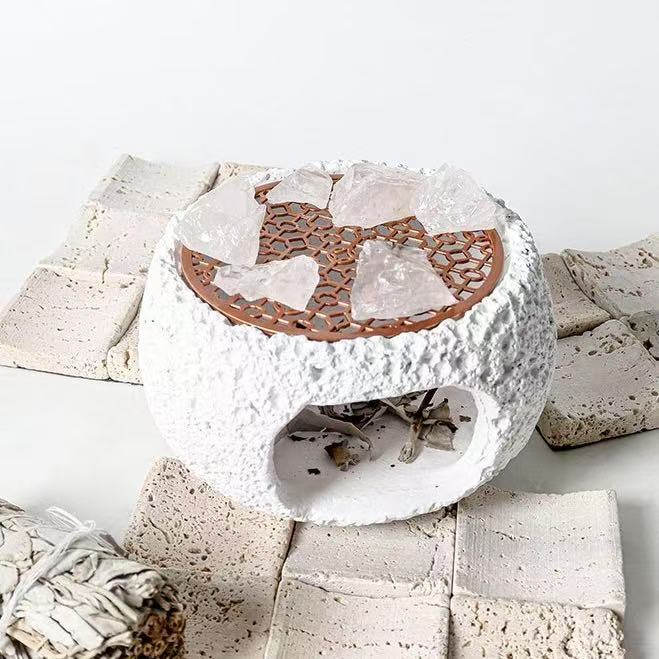 White cement crystal incense burner with rosewood grate and quartz crystals on top, placed on ceramic tiles with a white sage bundle for spiritual purification rituals