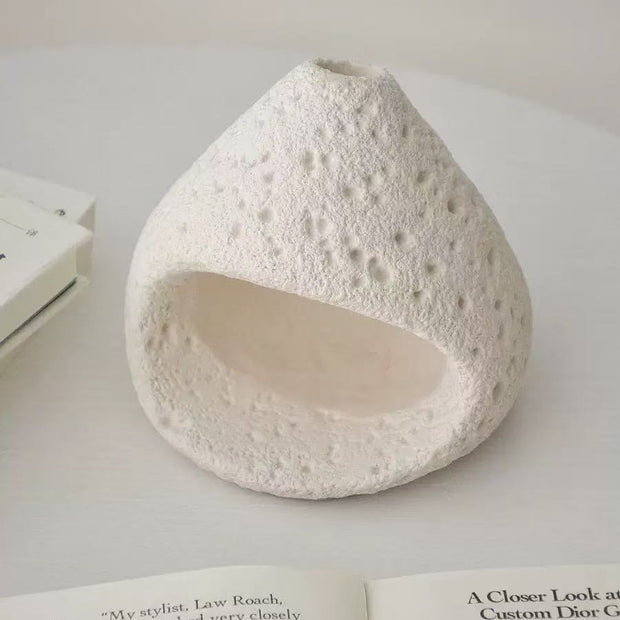 Natural white stone incense burner with porous surface texture, placed on an open book and neutral-toned background in a clean minimalist setting