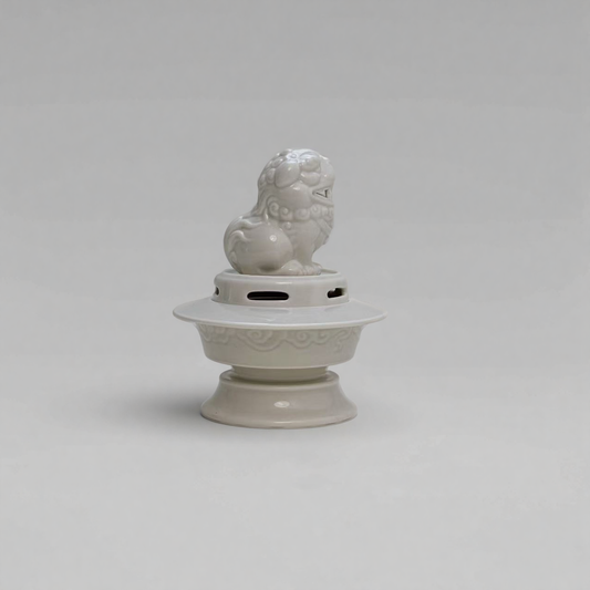 White ceramic Suanni guardian lion incense burner with traditional relief carving on a raised base