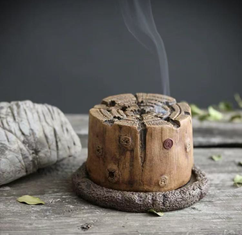 Hand-carved wood-stump style incense burner made from antique Yixing purple clay, releasing smoke on a rustic wooden surface
