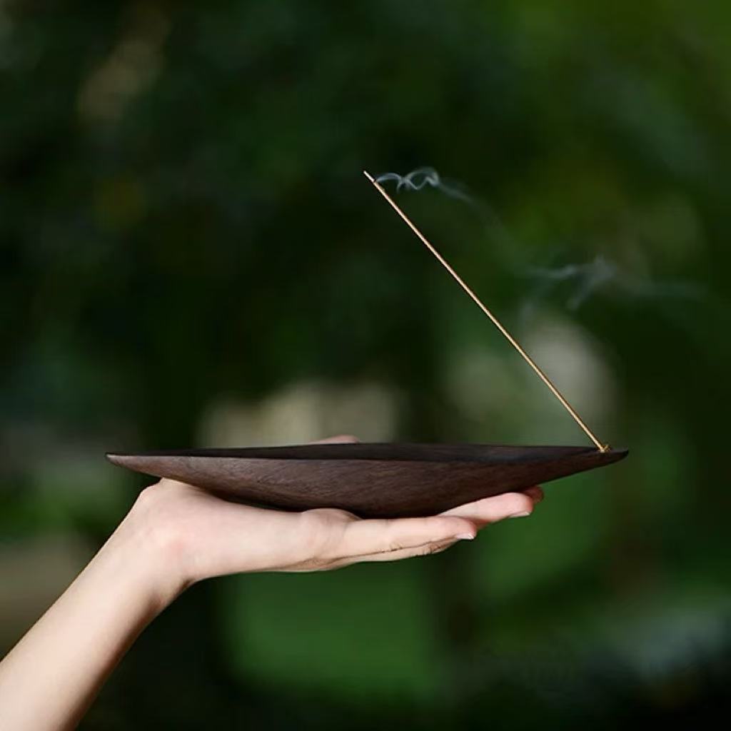Wooden boat incense holder held in hand with smoke
