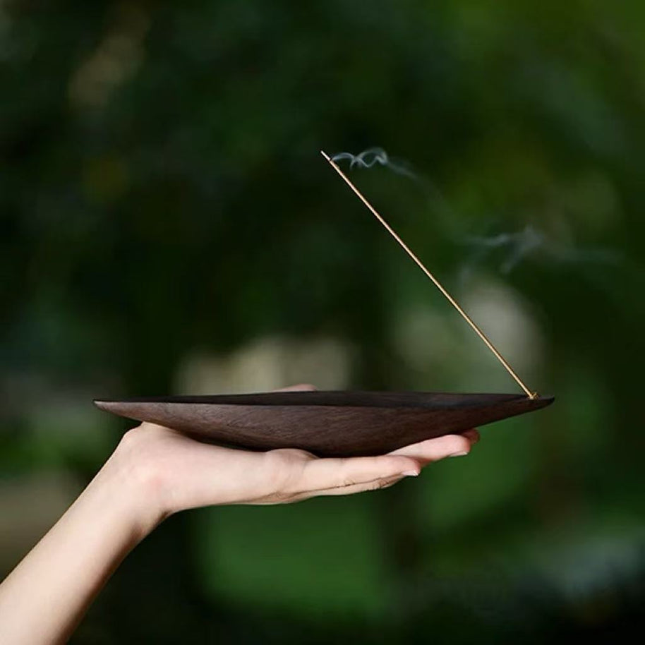 Wooden boat incense holder held in hand with smoke