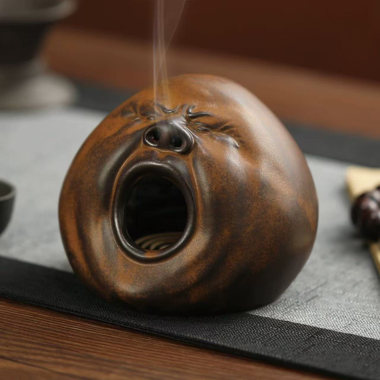 Quirky ceramic incense burner shaped like a yawning face with smoke flowing from the nose
