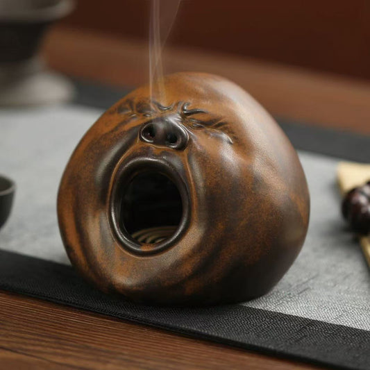 Quirky ceramic incense burner shaped like a yawning face with smoke flowing from the nose
